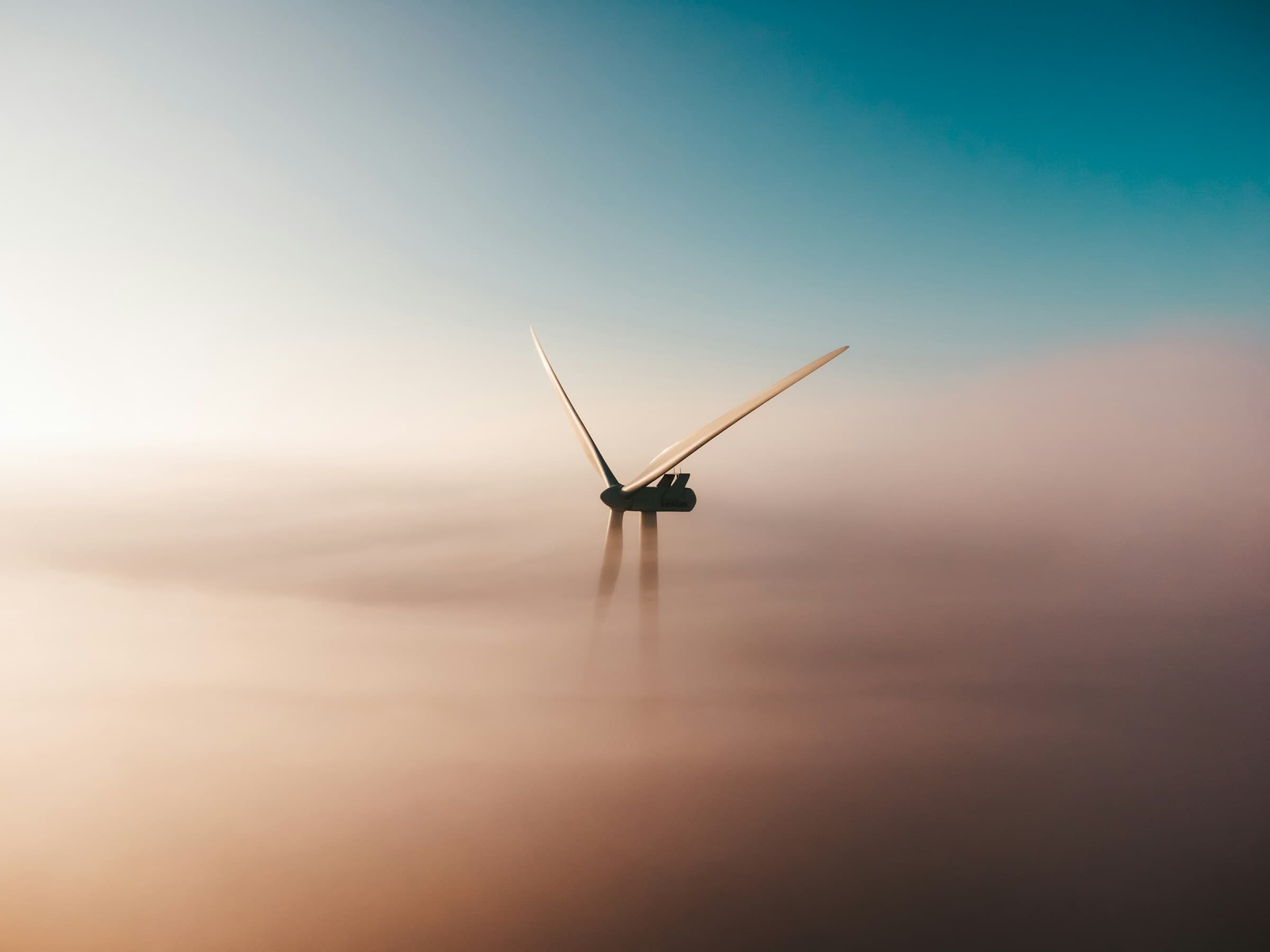 Éolienne émergeant de la brume au lever du soleil